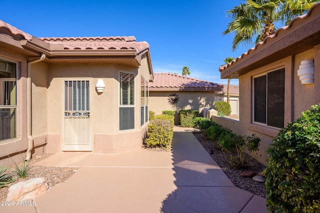 exterior space featuring a patio area, a tiled roof, and stucco siding