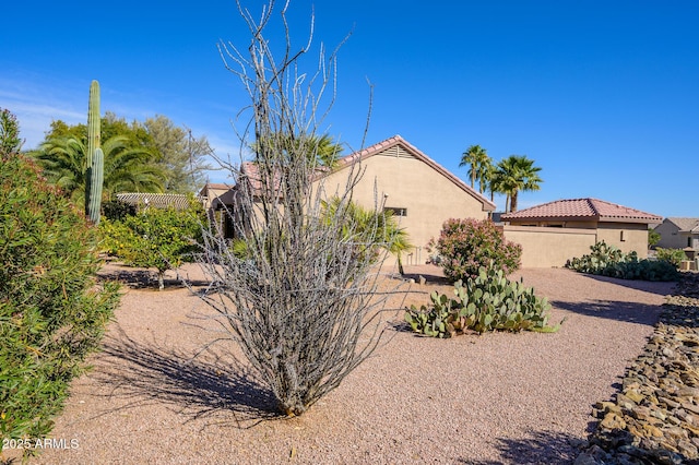 view of property exterior with a tile roof, fence, and stucco siding