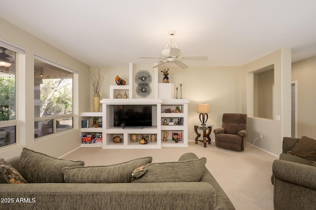 carpeted living area with a ceiling fan and baseboards