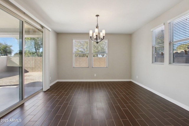 spare room featuring a chandelier, a wealth of natural light, and dark hardwood / wood-style floors