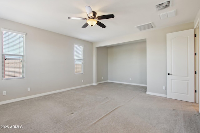 carpeted empty room featuring ceiling fan and a wealth of natural light