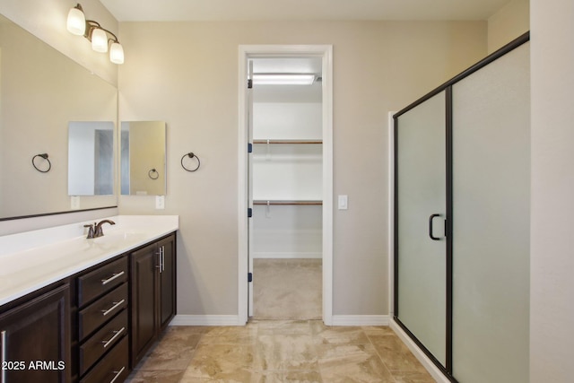 bathroom featuring a shower with door and vanity