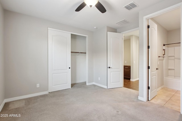 unfurnished bedroom featuring light colored carpet, ceiling fan, a closet, and connected bathroom