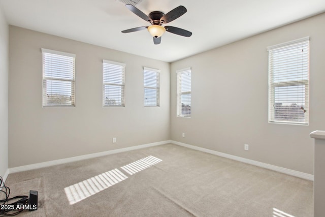 carpeted spare room featuring ceiling fan and a healthy amount of sunlight