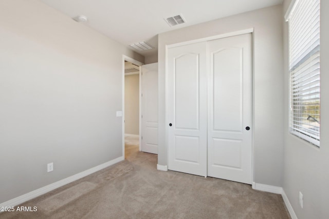 unfurnished bedroom with light carpet, a closet, and multiple windows