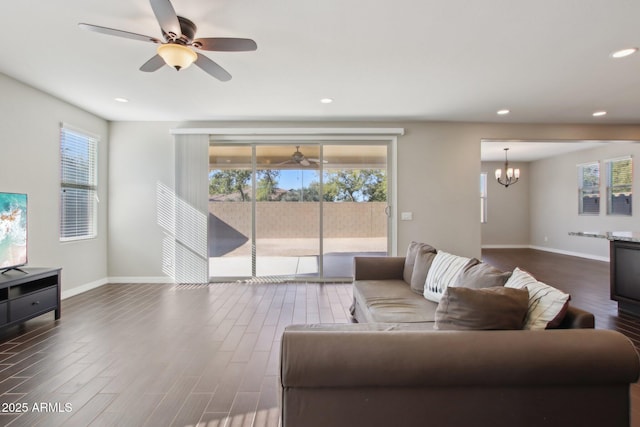 living room with ceiling fan with notable chandelier and dark hardwood / wood-style floors