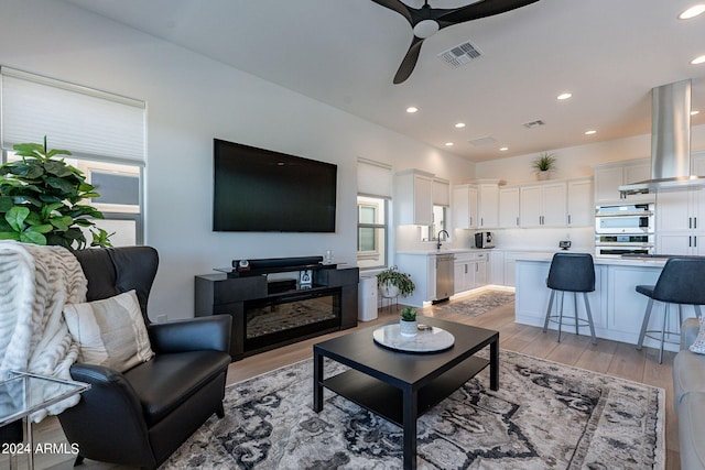 living room featuring sink, ceiling fan, and light wood-type flooring