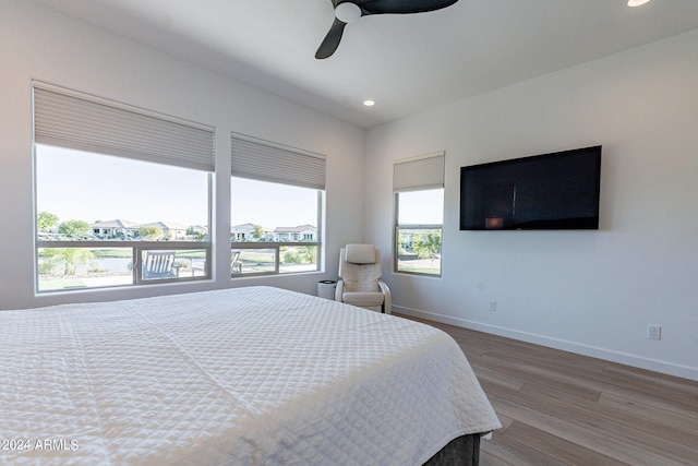 bedroom with wood-type flooring, ceiling fan, and multiple windows