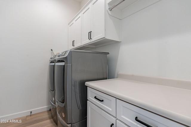 washroom featuring light hardwood / wood-style flooring, cabinets, and washing machine and clothes dryer