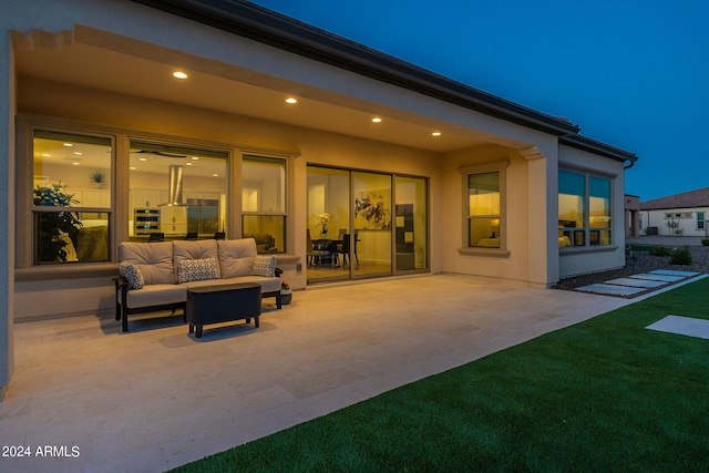 patio terrace at twilight with an outdoor living space and a yard