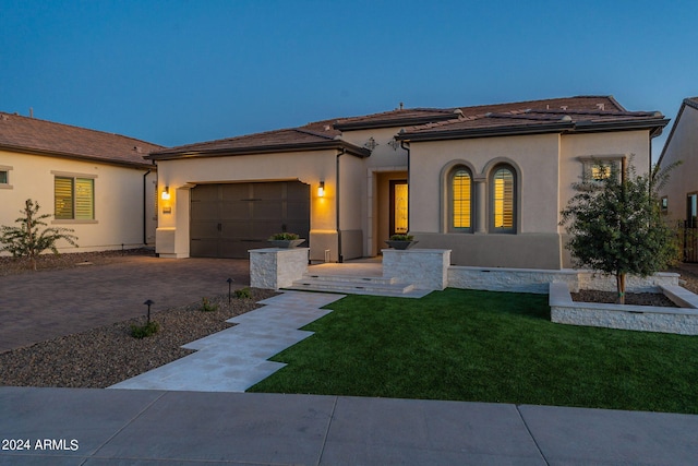 mediterranean / spanish-style house with a garage and a front lawn