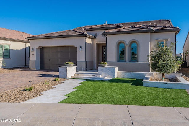 mediterranean / spanish house featuring a garage and a front yard