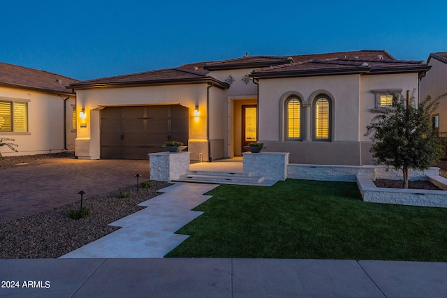 mediterranean / spanish-style home featuring a garage and a front lawn