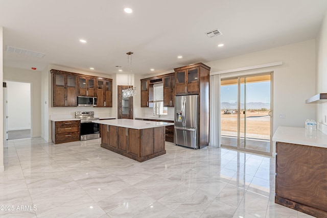 kitchen featuring dark brown cabinets, stainless steel appliances, sink, a center island, and hanging light fixtures