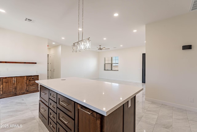 kitchen with pendant lighting, ceiling fan, a kitchen island, and dark brown cabinets