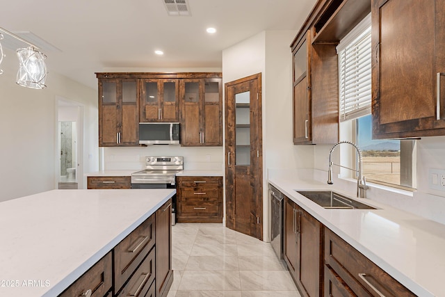 kitchen with decorative light fixtures, stainless steel appliances, and sink