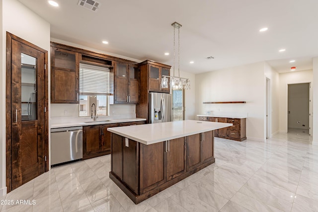 kitchen with appliances with stainless steel finishes, dark brown cabinets, sink, a center island, and hanging light fixtures