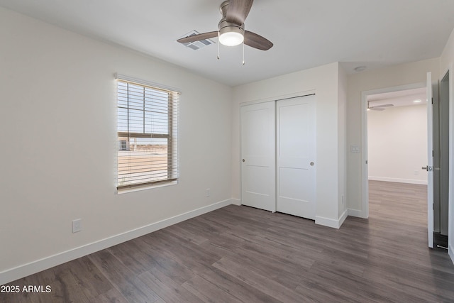 unfurnished bedroom featuring dark hardwood / wood-style flooring, ceiling fan, and a closet