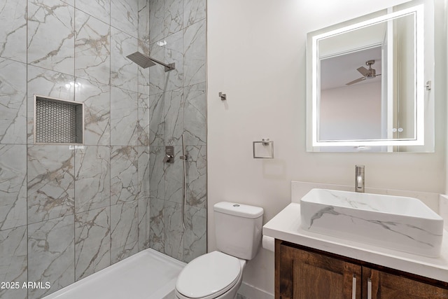 bathroom featuring vanity, toilet, and a tile shower