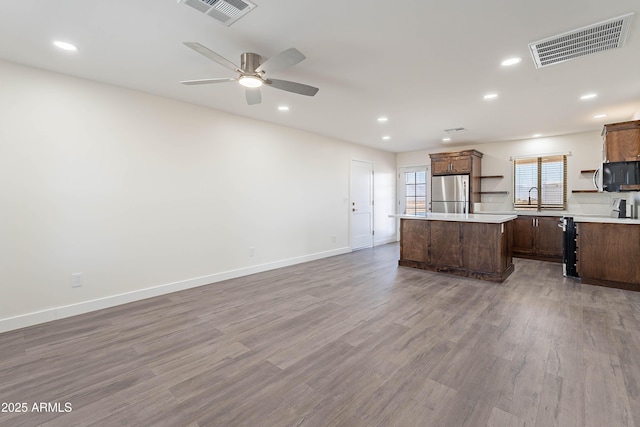 kitchen featuring ceiling fan, sink, hardwood / wood-style flooring, a center island, and stainless steel refrigerator