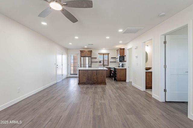 kitchen featuring appliances with stainless steel finishes, a center island, dark hardwood / wood-style floors, and ceiling fan