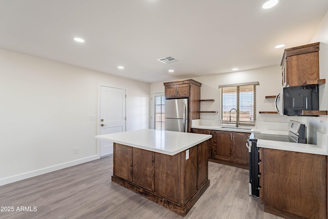 kitchen with a center island, sink, stainless steel appliances, plenty of natural light, and light hardwood / wood-style floors