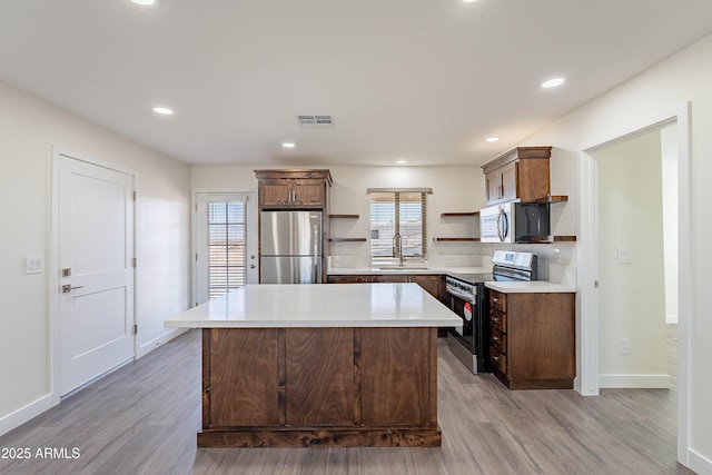 kitchen featuring a center island, sink, appliances with stainless steel finishes, and light hardwood / wood-style flooring