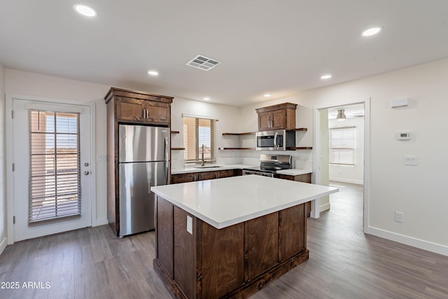 kitchen with sink, a kitchen island, a healthy amount of sunlight, and appliances with stainless steel finishes