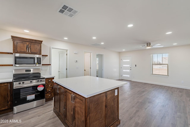 kitchen featuring ceiling fan, a center island, light wood-type flooring, and appliances with stainless steel finishes