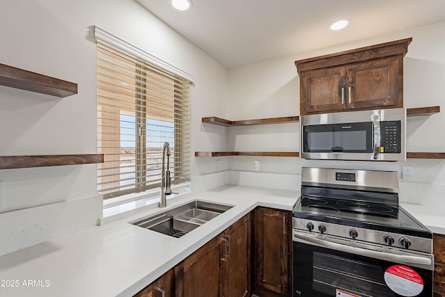 kitchen with appliances with stainless steel finishes, dark brown cabinetry, and sink