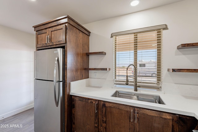 kitchen featuring stainless steel fridge, light hardwood / wood-style floors, and sink