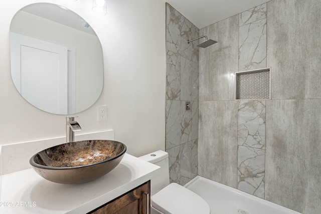 bathroom with vanity, toilet, and a tile shower