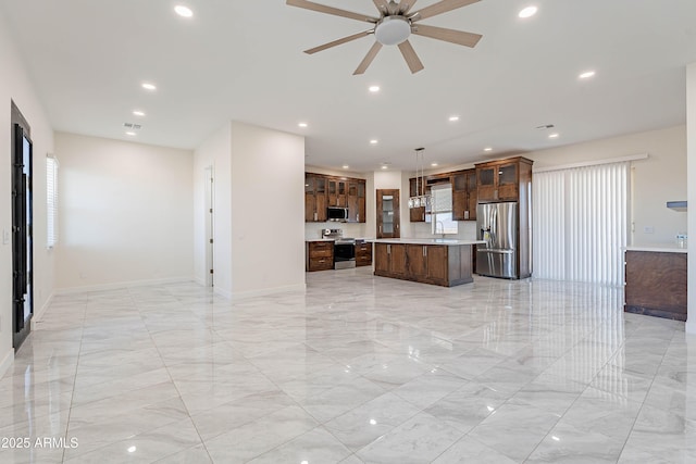 kitchen featuring stainless steel appliances, ceiling fan, sink, a kitchen island, and hanging light fixtures