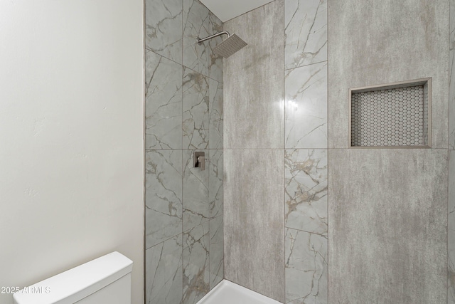 bathroom featuring tiled shower and toilet