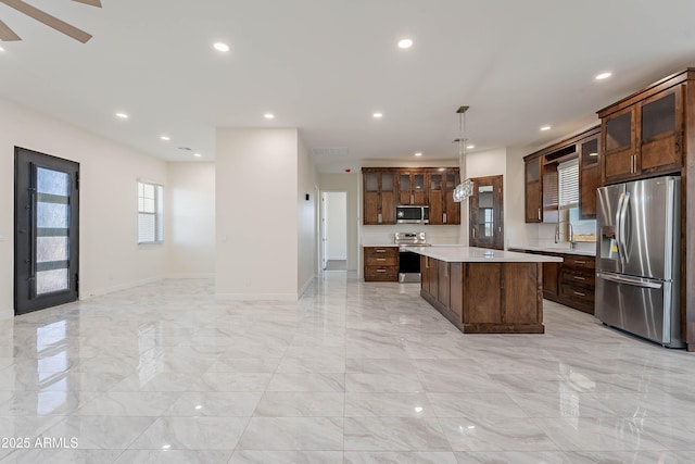 kitchen featuring a center island, sink, hanging light fixtures, appliances with stainless steel finishes, and dark brown cabinets