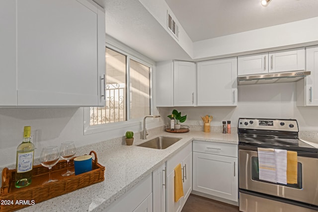 kitchen featuring stainless steel range with electric stovetop, sink, light stone counters, and white cabinets