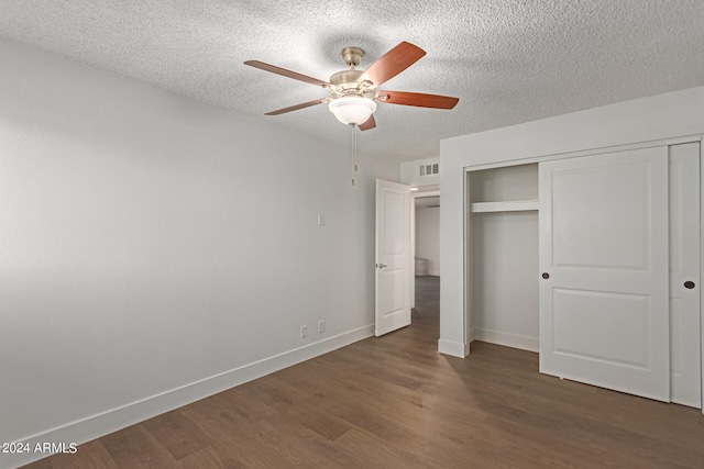 unfurnished bedroom with ceiling fan, a textured ceiling, a closet, and dark hardwood / wood-style floors