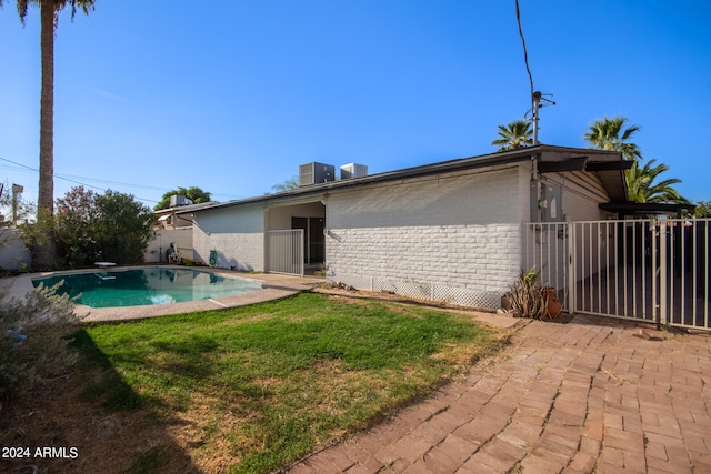 rear view of property featuring a lawn, a patio, and a fenced in pool