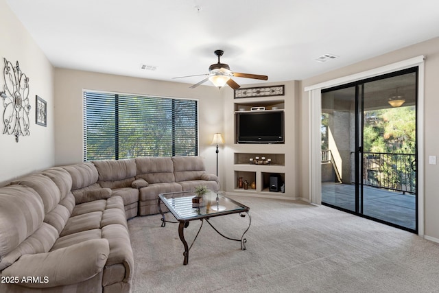 living room featuring a fireplace, light colored carpet, and ceiling fan