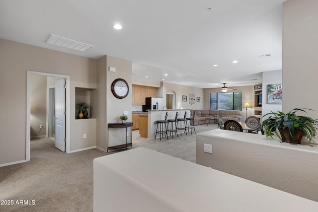 kitchen featuring a breakfast bar area, visible vents, open floor plan, light carpet, and refrigerator with ice dispenser