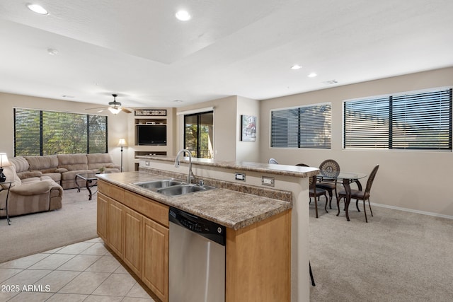 kitchen featuring light carpet, open floor plan, a kitchen island with sink, stainless steel dishwasher, and a sink