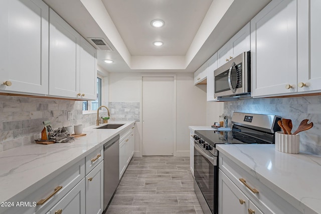 kitchen featuring light stone counters, sink, white cabinetry, and stainless steel appliances