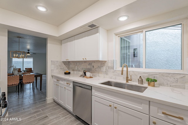 kitchen featuring stainless steel dishwasher, light stone countertops, white cabinetry, and sink