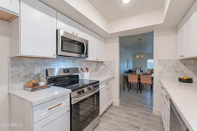 kitchen with white cabinetry, appliances with stainless steel finishes, and an inviting chandelier