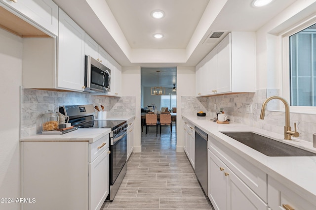 kitchen featuring a raised ceiling, sink, white cabinets, and stainless steel appliances