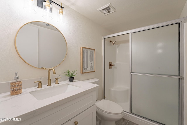 bathroom with vanity, toilet, and a shower with door