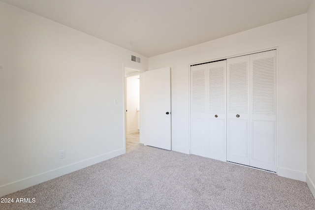 unfurnished bedroom with light carpet and a closet