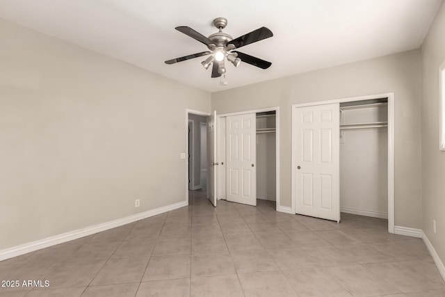 unfurnished bedroom with light tile patterned floors, ceiling fan, baseboards, and multiple closets