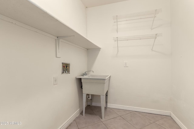 laundry room featuring laundry area, hookup for a washing machine, baseboards, and light tile patterned floors