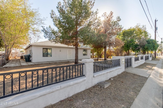 view of front of home with a fenced front yard, a gate, and stucco siding